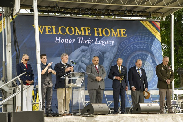Welcome_Home_Opening_Ceremony_Chaplain_Gives_Invocation_with_Speakers_in_Background